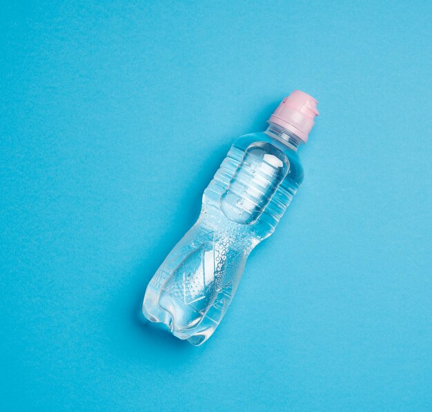 Photo transparent plastic bottle with fresh water on a blue background top view