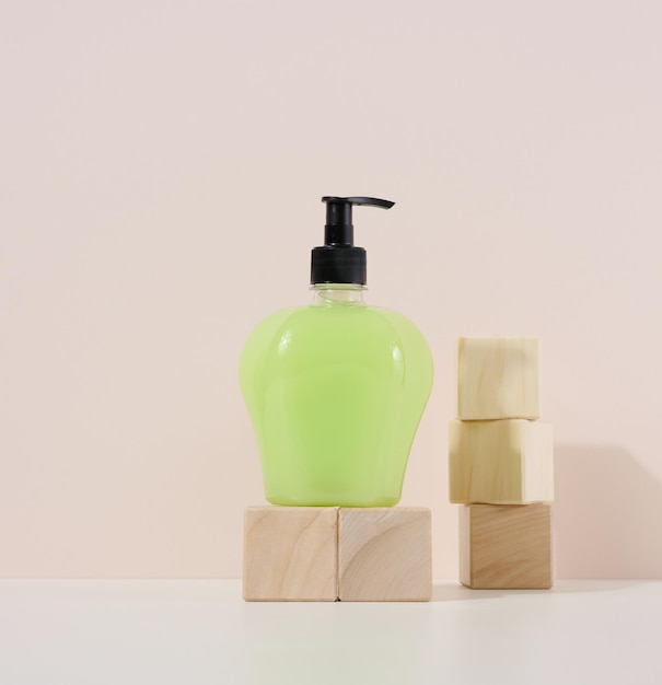 Transparent plastic bottle with green liquid on a wooden podium