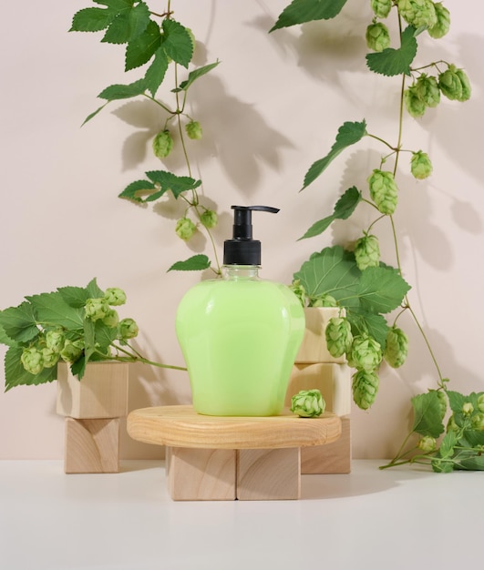 Transparent plastic bottle with green liquid on a wooden podium