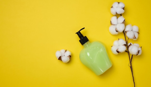 Transparent plastic bottle with green liquid on a yellow background