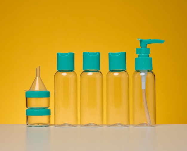 Transparent plastic bottles for liquid cosmetics on a yellow background