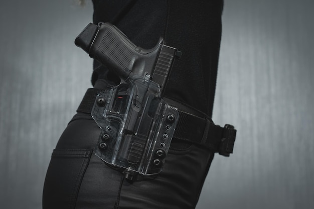 A transparent plastic holster with a pistol on a girl's belt closeup photo High quality photo