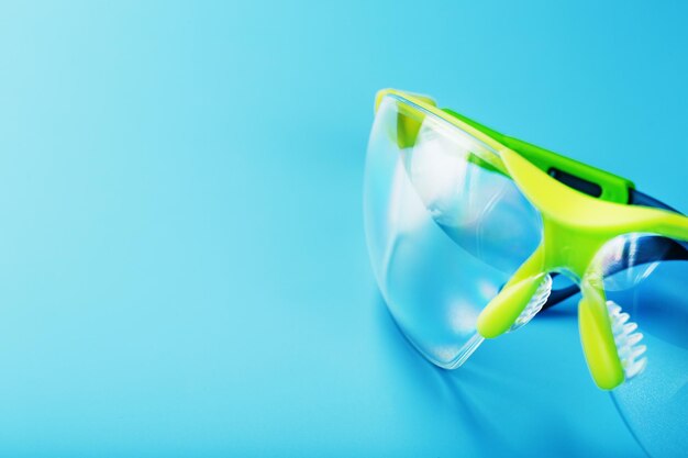 Transparent polycarbonate safety glasses on a blue background.