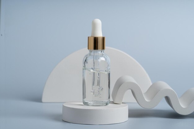 A transparent serum or gel in a dropper bottle on a white podium product presentation