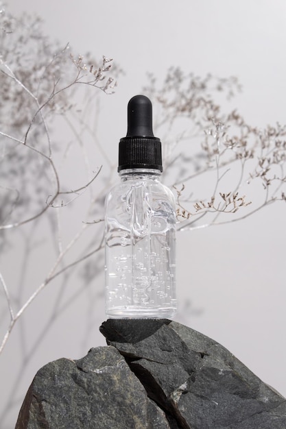 Transperent glass dropper bottle with a pipette on stones grey background Natural cosmetics concept natural essential oil