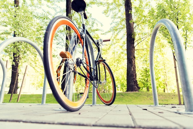 transport, storage, security and safety concept - close up of fixed gear bicycle locked at street parking outdoors