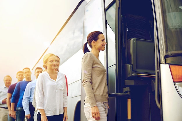 Photo transport, tourism, road trip and people concept - group of happy passengers boarding travel bus