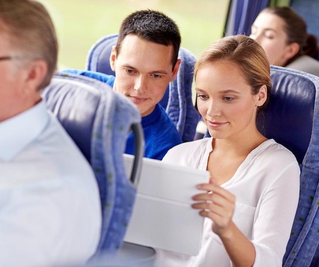 Photo transport, tourism, road trip, technology and people concept - happy couple with tablet pc in travel bus