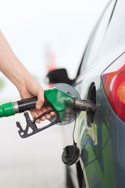 transportation and ownership concept - man pumping gasoline fuel in car at gas station