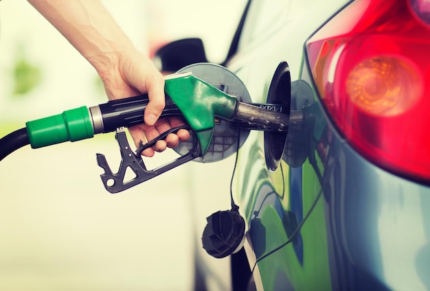 transportation and ownership concept - man pumping gasoline fuel in car at gas station