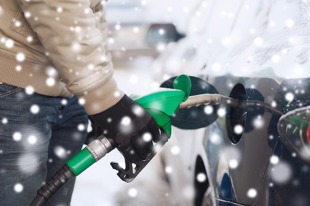 transportation, tanking, people and vehicle concept - close up of man with fuel hose nozzle tanking car