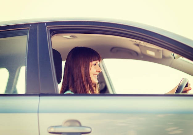 transportation and vehicle concept - happy woman driving a car