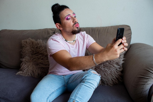 Transsexual guy taking a selfie or a video call with his mobile at home