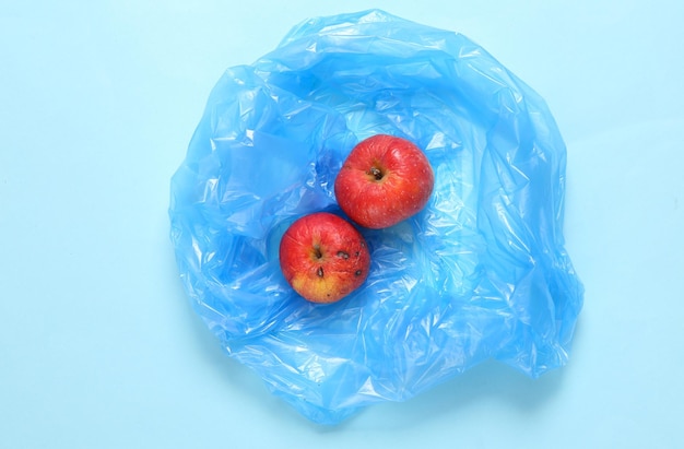 Trash packege with spoiled apples on blue background