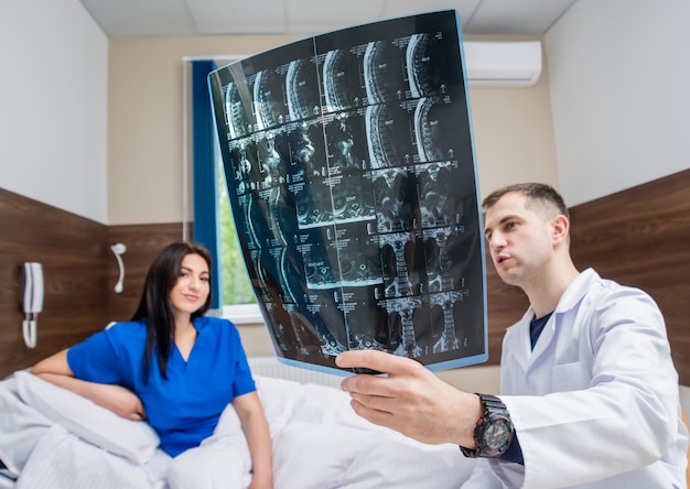 Traumatologist showing MRI film to patient in hospital.