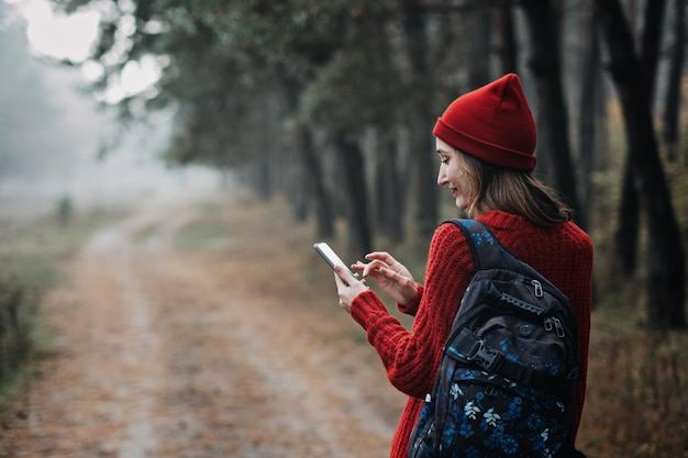 Travel apps young woman traveler with backpack holding smartphone device in hands