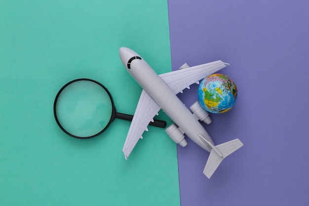 Travel concept. Airplane, magnifier with a globe on purple blue