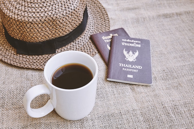 Travel concept, A cup of black coffee, weave hat and Thai citizen passport