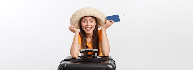 Travel concept studio portrait of pretty young woman holding passport and luggage isolated on white