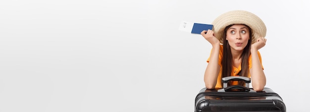 Travel concept studio portrait of pretty young woman holding passport and luggage isolated on white