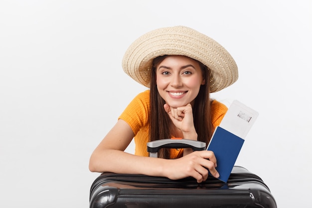 Travel concept. Studio portrait of pretty young woman holding passport and luggage. Isolated on white