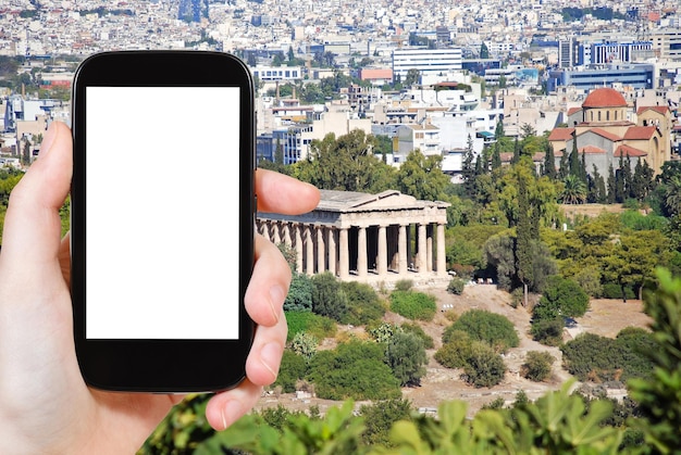 travel concept - tourist photograph Temple of Hephaestus and Athens city view from Acropolis hill, Greece on smartphone with cut out screen with blank place for advertising logo