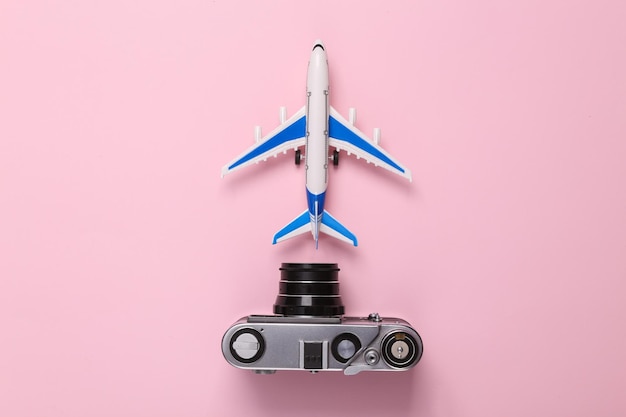 Photo travel concept toy model of passenger plane with camera on pink pastel background top view