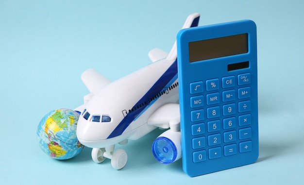 Travel concept Toy passenger plane calculator and globe on a blue pastel background