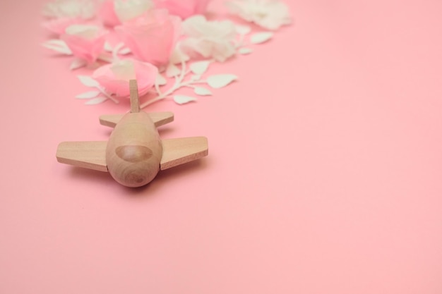 Travel concept with wood plane and paper flowers, petals on pink background.. Top view, flat lay. Copy space. Trip, vacation concept.