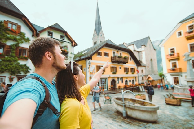 Travel couple in hallstatt austria point straight ahead