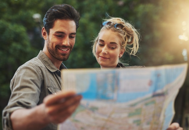 Travel couple and reading map in nature for adventure holiday or directions in Budapest Tourist young woman and happy man with document for location search destination or outdoor sightseeing