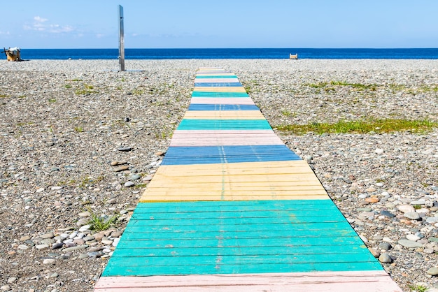 travel to Georgia colorful wooden path to sea on pebble beach in Batumi city on sunny autumn day