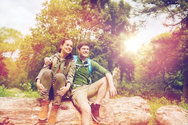 Photo travel, hiking, backpacking, tourism and people concept - smiling couple with backpacks resting and hugging in nature