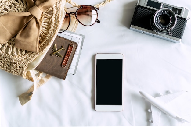 Travel items of a traveler woman with sunglasses, bag, passport and mobile phone on bedroom at home.