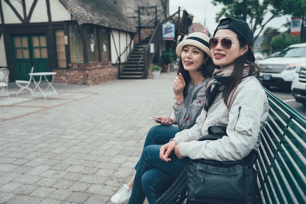 Travel people talking sitting on bench on street