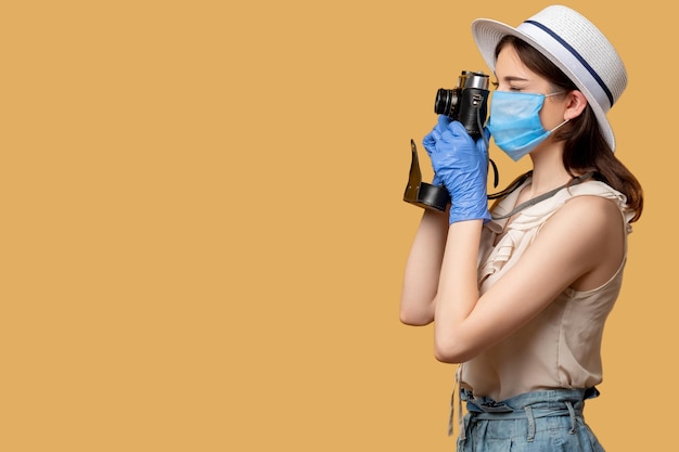 Travel photo Covid19 restriction Capture holiday memories Stay safe Woman in protective mask gloves taking picture on retro camera isolated on beige copy space side view