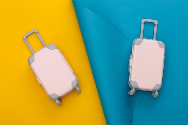 Travel planning. Two Toy travel luggage on blue yellow. Flat lay.