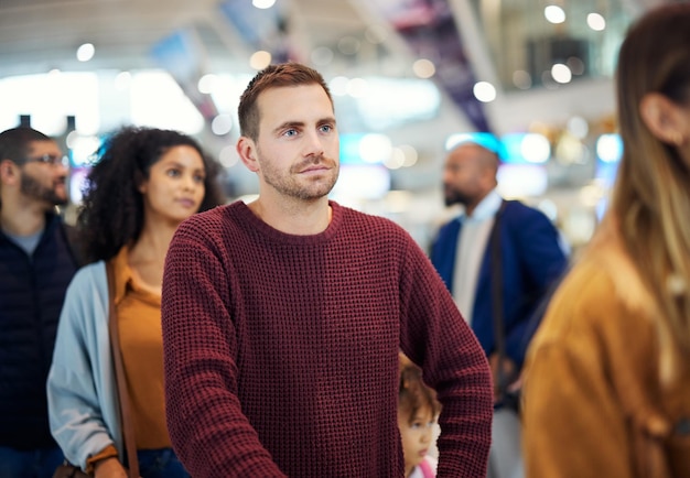 Travel queue and serious with man in airport for vacation international trip and tourism Holiday luggage and customs with passenger in line for ticket departure and flight transportation