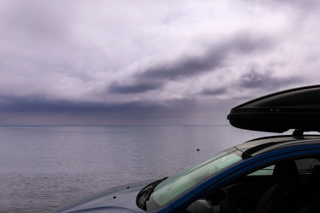 Travel to the sea by car. Crossover with roof rack stands against the background of the sea.