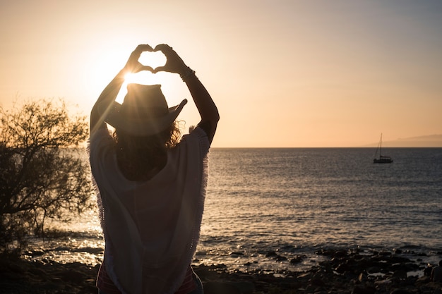 Travel and summer holiday vacation concept with unrecognizable people woman  viewed from back doing hearth sign with