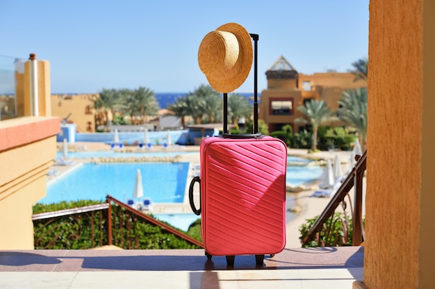 Travel, summer holidays and vacation concept. pink suitcase with hat