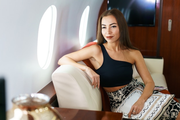 Travel and technology flying first class a pretty young business woman is sitting on the plane fashi...