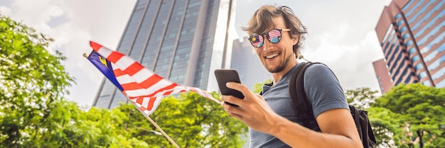 Travel and technology young man tourist with the flag of malaysia is looking at a city map in a