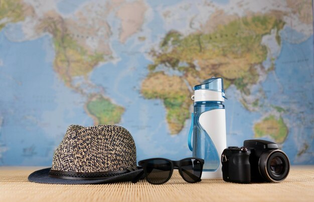 Photo travel theme hat sunglasses bottle and camera background world map