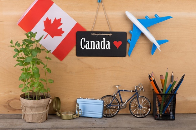 Travel time concept blackboard with text Canada love flag of the Canada airplane model little bicycle and suitcase compass