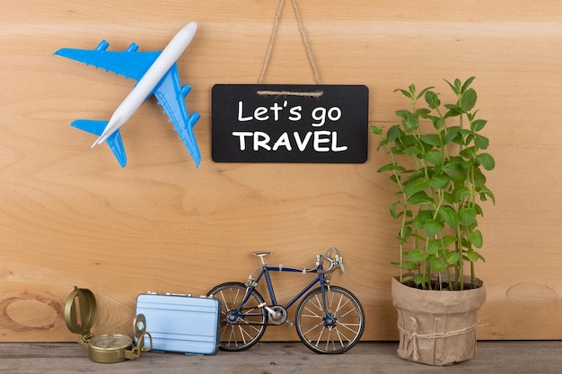 Travel time concept blackboard with text Let's go travel airplane model little bicycle and suitcase