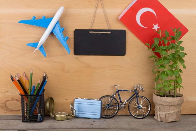 Travel time concept blank blackboard flag of the Turkey airplane model little bicycle and suitcase compass on wooden background