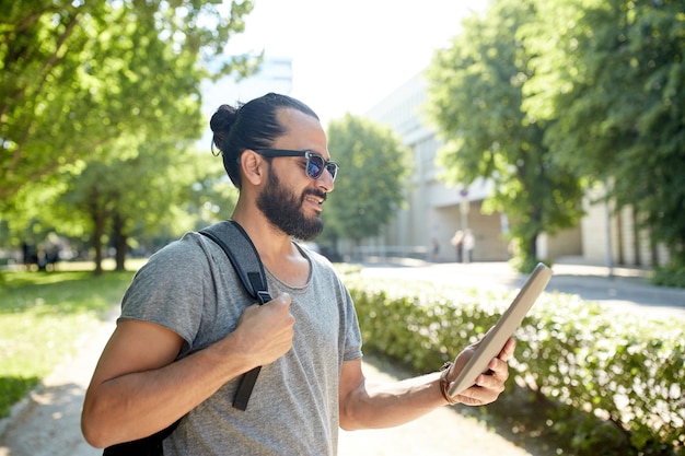 travel, tourism, backpacking, technology and people concept - man traveling with backpack and tablet pc computer in city searching location