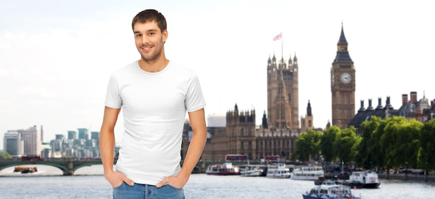 travel, tourism and people concept - smiling man in blank white t-shirt over london city background