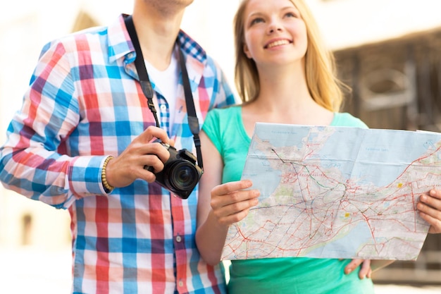 travel, tourism, technology and people concept - close up of couple with map and digital camera in city